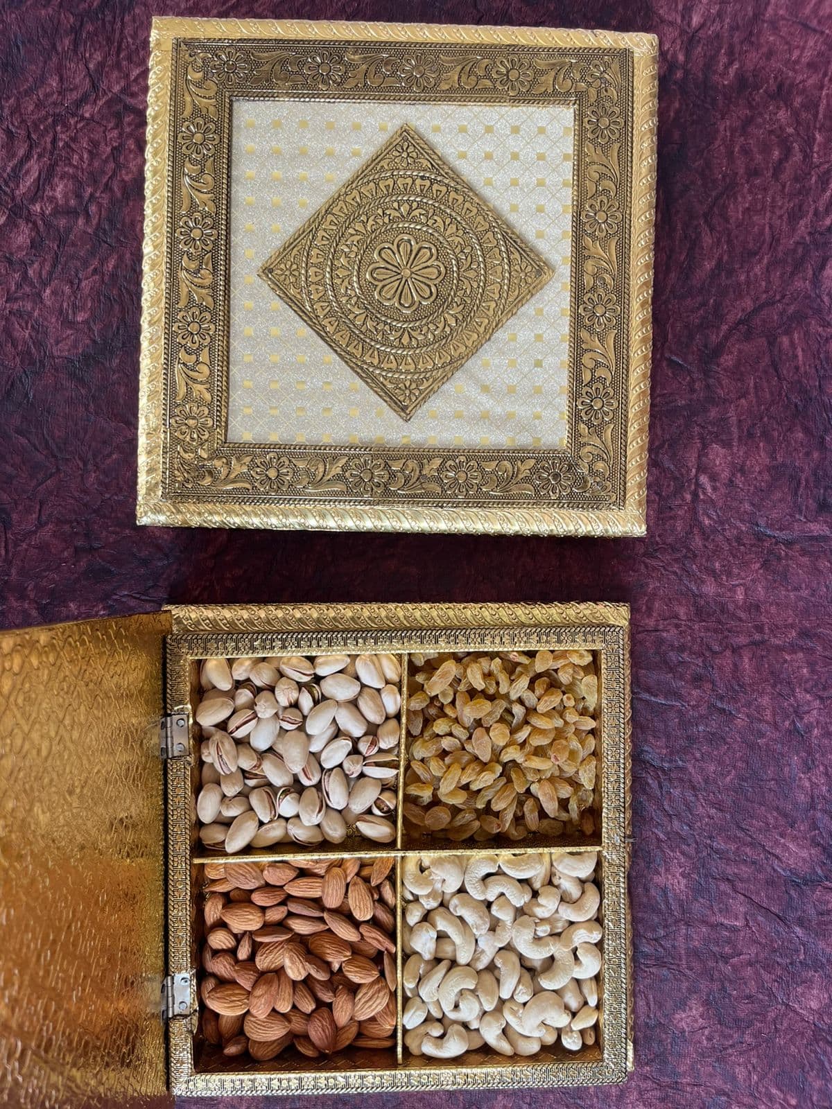 Gold floral Rakhi gift box beside an open dry fruit box